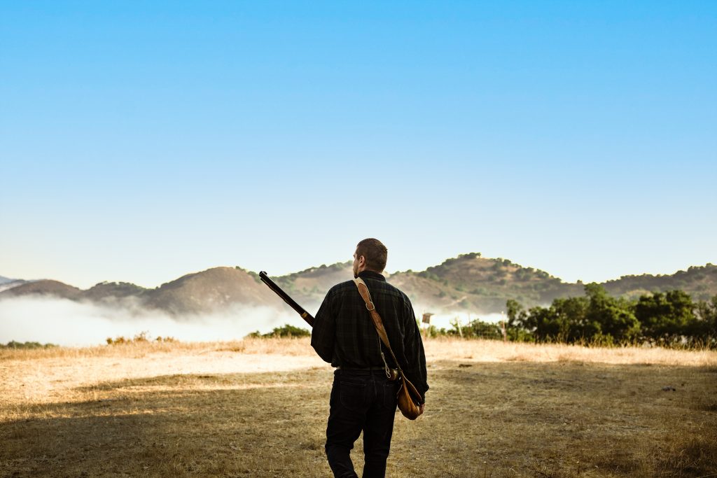 Hunter heading into the hills with musket.